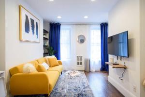 uma sala de estar com um sofá amarelo e uma televisão de ecrã plano em 69-4A Quality NEW Prime Lower East East 1br Apt em Nova York