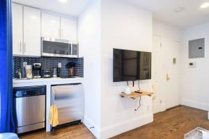 eine Küche mit weißen Schränken und einem Flachbild-TV in der Unterkunft 69-4A Quality NEW Prime Lower East East 1br Apt in New York