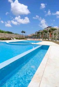 an empty swimming pool with blue water and buildings at Relaxing condo near airport PUJ Pool/Wi-fi in Punta Cana