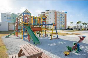 um parque infantil com escorrega e um banco em Relaxing condo near airport PUJ Pool/Wi-fi em Punta Cana