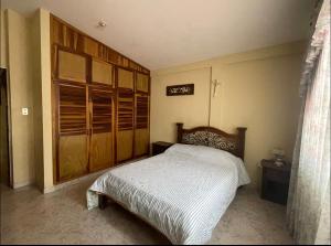 Schlafzimmer mit einem Bett und Holzschränken in der Unterkunft Casa en San Cristóbal, urb los naranjos in San Cristóbal