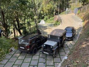 two jeep and a truck parked on a sidewalk at Wetlands Wayanad Resort with Natural Waterfalls in Padinjarathara