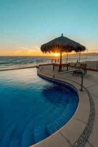 a swimming pool with a table and an umbrella and the ocean at Tai Condo 3 in Barra de Navidad