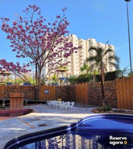 a swimming pool with tables and chairs and a building at FLAT Golden Dolphin Express in Caldas Novas