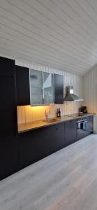 a kitchen with black cabinets and a sink at Lofoten Rorbu - Odin bua in Stamsund
