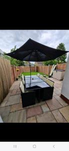 a table with an umbrella on a patio at Lovely 3 bedroom house free parking in Luton