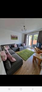 a living room with a gray couch and a green rug at Lovely 3 bedroom house free parking in Luton