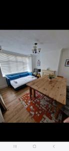 a living room with a wooden table and a bed at Lovely 3 bedroom house free parking in Luton