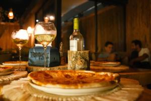 una mesa con un plato de pizza y una copa de vino en Búho Kite Hotel Boutique, en Salina de Rey
