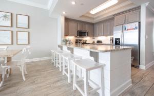 a kitchen with a large island with white stools at Phoenix Orange Beach II 2003 in Orange Beach