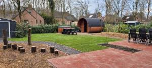 a garden with a wooden barrel in a yard at Evergreen wellness met sauna & hottub in Ewijk