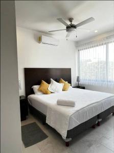 a bedroom with a large bed with a ceiling fan at Fast WIFI/5 min beach/Private Parking in Playa del Carmen +30 photos