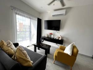 a living room with a couch and a table and a television at Fast WIFI/5 min beach/Private Parking in Playa del Carmen