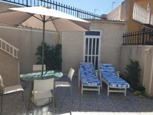 patio con tavolo, sedie e ombrellone di El Caprichito a 200 metros de la playa! a Santiago de la Ribera