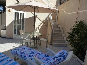 een patio met een tafel en stoelen en een parasol bij El Caprichito a 200 metros de la playa! in Santiago de la Ribera