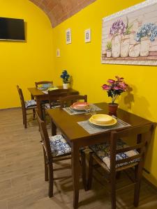 comedor con paredes amarillas y mesas y sillas de madera en A casa di Bice, en Case Nuove