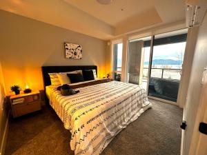 1 dormitorio con cama grande y ventana grande en Dreamy Panoramic Lakeview 1 Bedroom plus Den, en Harrison Hot Springs