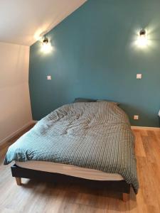 een bed in een slaapkamer met een blauwe muur bij Le Perchoir in Saint-Jans-Cappel