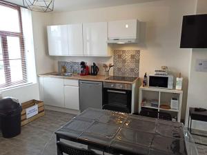 a kitchen with white cabinets and a stove top oven at Le Perchoir in Saint-Jans-Cappel +4 photos