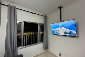 telewizor z płaskim ekranem wiszący na ścianie obok okna w obiekcie Apartamento *Vista da Ilha* - Novo Lançamento! w mieście São Vicente
