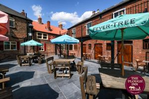 a patio with tables and chairs and umbrellas at The Plough Inn in Snaith