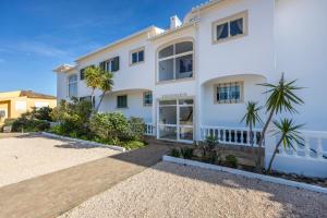 a white house with palm trees in front of it at Apartamento Meia Praia in Lagos