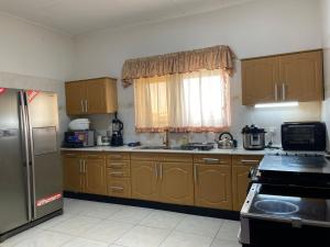 a kitchen with wooden cabinets and a sink and a refrigerator at AGASTEV Guesthouse GH in Accra