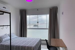 - une chambre avec un lit et une grande fenêtre dans l'établissement Apartamento Paraíso da Ilha Porchat ! *Novíssimo!*, à São Vicente
