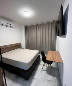- une chambre avec un lit, une table et une télévision dans l'établissement Apartamento Paraíso da Ilha Porchat ! *Novíssimo!*, à São Vicente