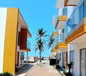 una fila de edificios con una palmera en el fondo en HERMOSOS APARTAMENTOS FRENTE AL MAR EN EL CONDOMINIO PALMAR DE LOS VIENTOS, en San Bernardo del Viento