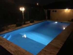 una piscina illuminata di notte di Just Like Home Bed & Spa Porsgrunn a Porsgrunn