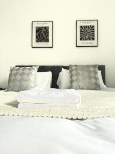 a white bed with two pictures on the wall at Mideyah Stays - 3 Bed Comfy House in Cardiff