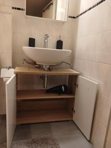 La salle de bains est pourvue d'un lavabo blanc sur une étagère en bois. dans l'établissement Ferienwohnung in Bühler, à Bühler