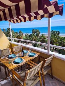 een tafel met stoelen en een parasol op een balkon met uitzicht op de oceaan bij Los Cuentos De Natalia / The Tales Of Natalia in Oropesa del Mar