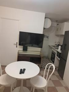 uma pequena cozinha com uma mesa branca e cadeiras em Grand Studio de 24m2 avec terrasse privée proche de la gare RER TER em Étampes