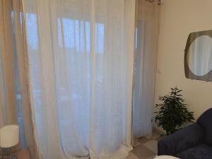 uma janela com cortinas brancas numa sala de estar em Grand Studio de 24m2 avec terrasse privée proche de la gare RER TER em Étampes