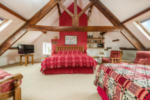 a bedroom with a red bed and two chairs at Kidwelly Farmhouse B&B in Kidwelly