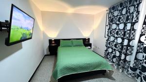a small bedroom with a green bed and a tv at Apartaestudio Reloj in Líbano