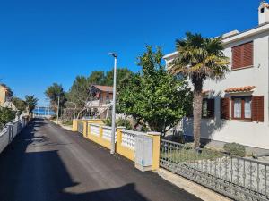 an empty street with a fence and a palm tree at Apartman Car in Vir