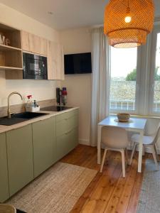 - une cuisine avec une table, un évier, une table et une fenêtre dans l'établissement Lescale Donvillaise, à Donville-les-Bains