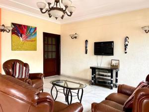 sala de estar con muebles de cuero y TV de pantalla plana en Appart 3 Ch. Biteng Yaoundé, en Yaoundé