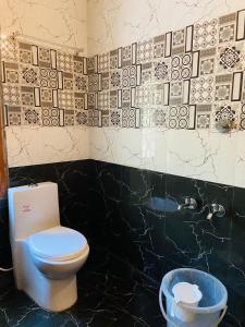 a bathroom with a toilet and a trash can at Deer Suites and Spa- Rock Beach White Town Zone , French Quarter, Pondicherry in Puducherry