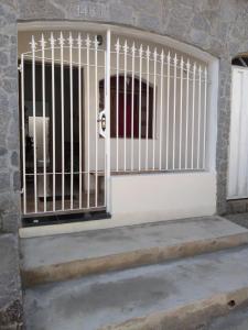 uma porta branca com um portão num edifício em kitnet em São João Del Rei, a 11km de Tiradentes MG em São João del Rei