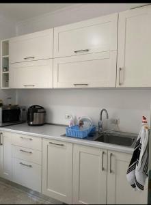 una cocina blanca con armarios blancos y fregadero en 29 Guesthouse en Bajram Curri