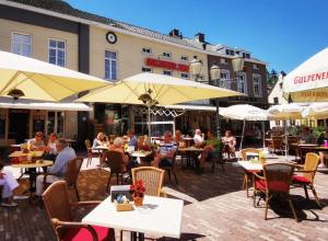 a group of people sitting at tables in an outdoor restaurant at Herberg de Zwarte Ruiter in Gulpen
