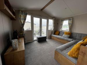 a living room with a couch and a large window at Great 8 Berth Caravan With Decking At Valley Farm, Ref 46238pl in Great Clacton