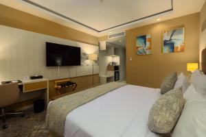 Habitación de hotel con cama, escritorio y TV. en 2H Hotel en Orán