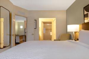 um quarto com uma grande cama branca e uma cadeira em Staybridge Suites Tallahassee I-10 East, an IHG Hotel em Tallahassee