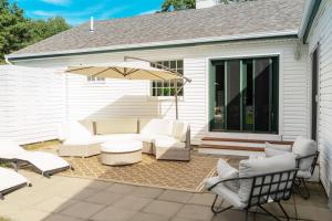 un patio con muebles blancos y una sombrilla en Casa Hermes in Hamptons, en Westhampton Beach