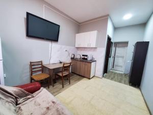a living room with a table and a kitchen with a tv at ARMONIE AIRPORT Studio in Băcioi